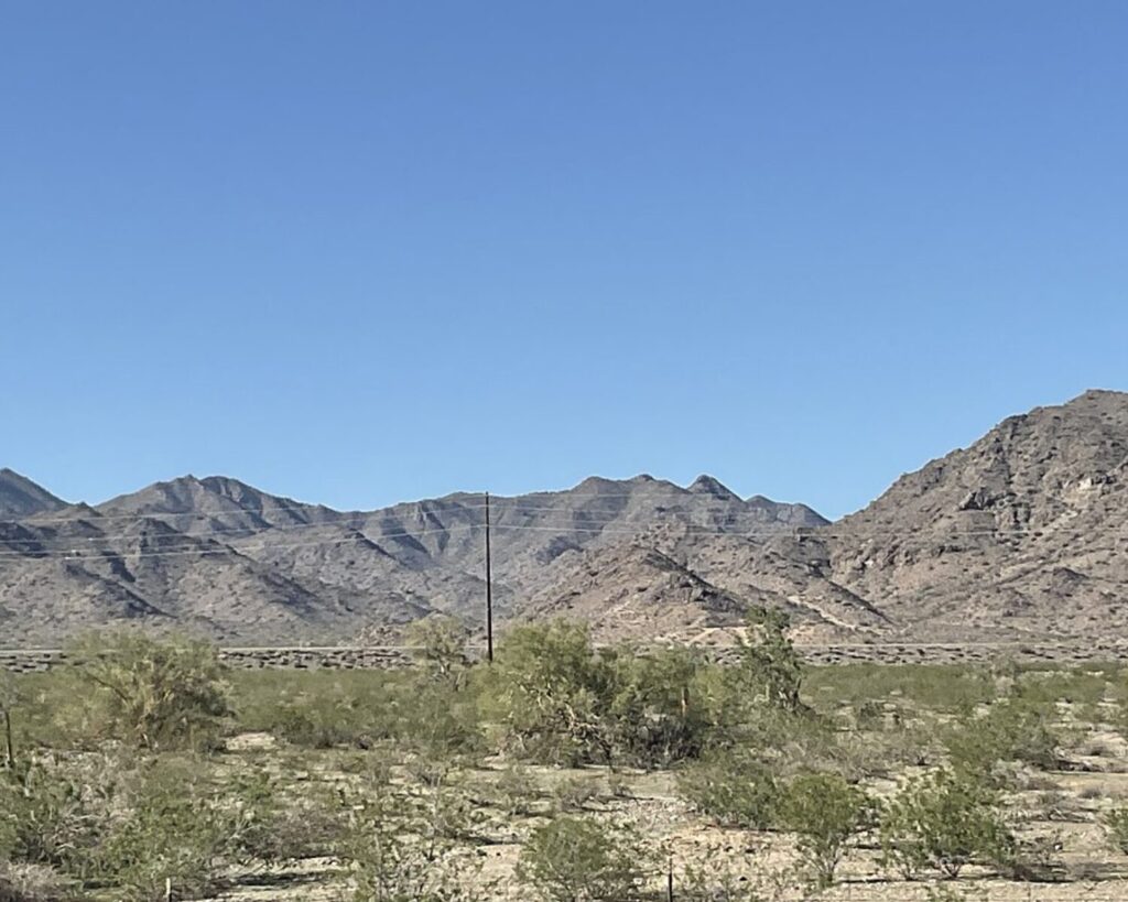 Buckeye, Arizona desert hills with sparse shrubs under a clear blue sky.