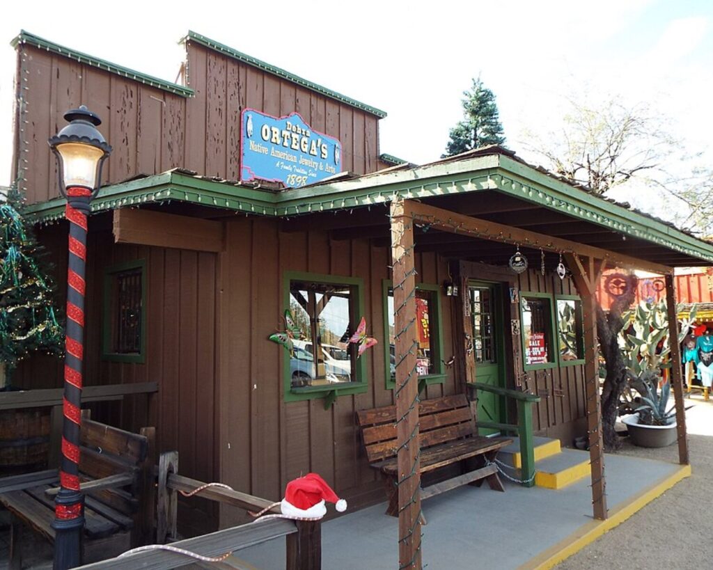 Ortega’s Frontier Town building in Cave Creek with a rustic wooden storefront, porch, benches, and decorative streetlamp.
