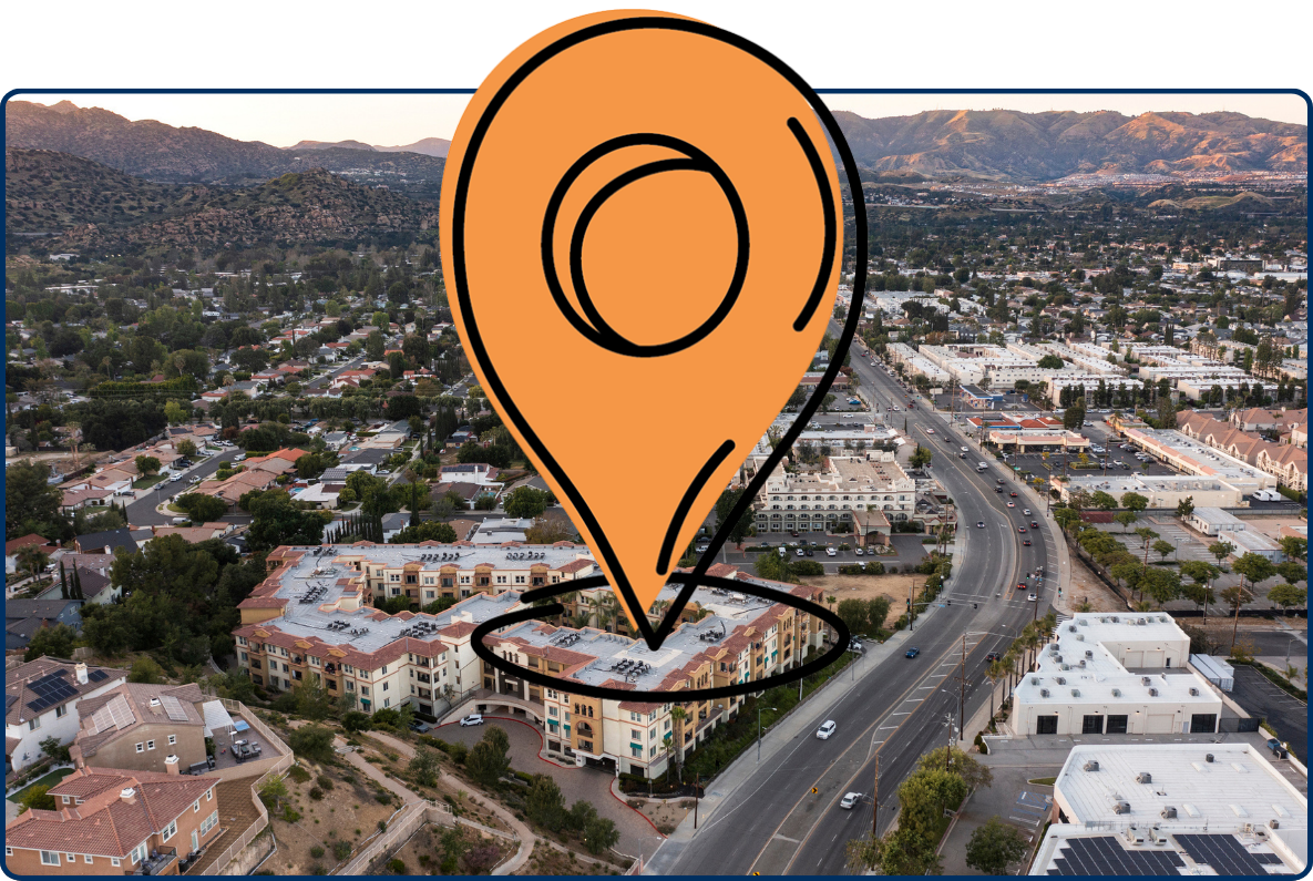 Aerial view of Chatsworth, California urban center with roads, buildings, homes, and surrounding mountains.