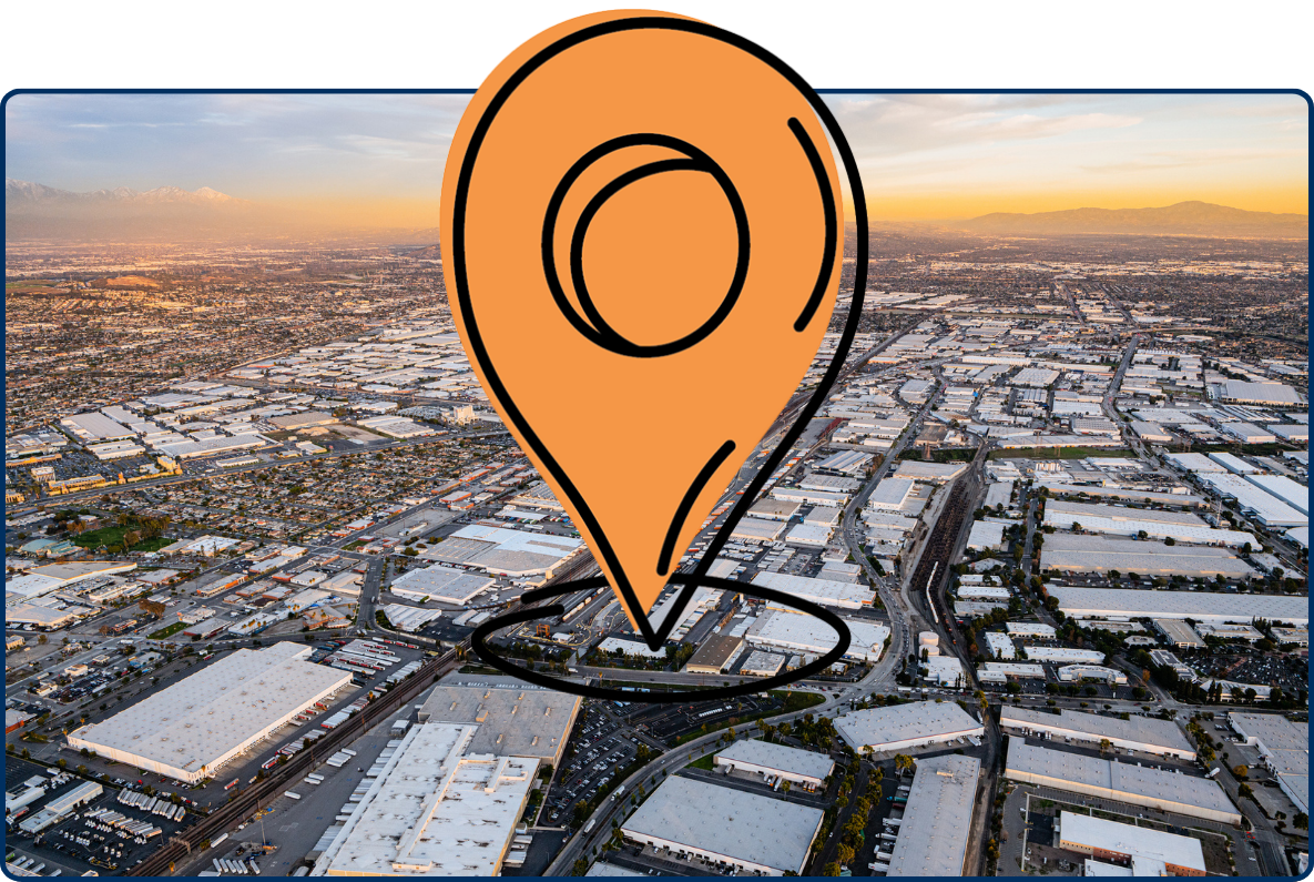 Aerial view of industrial Commerce, California with warehouses, rail lines, roads, and sunset sky.