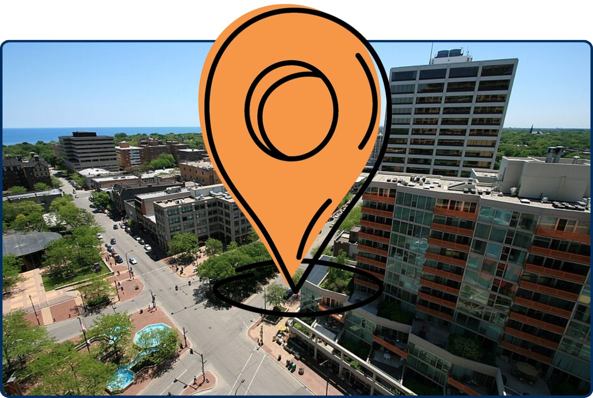Aerial view of Fountain Square in Evanston with city streets, high-rise buildings, Lake Michigan, and clear blue sky.