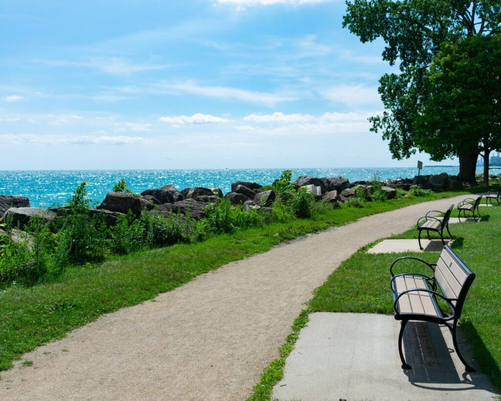 Benches along a Lake Michigan park path in Evanston, Illinois with rocks, trees, and blue water.