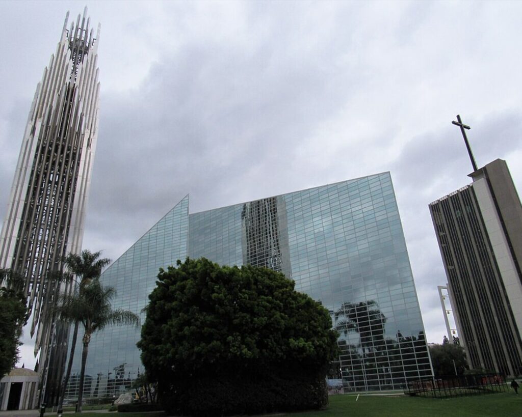 Christ Cathedral campus in Garden Grove, California with glass architecture, tower, cross, and cloudy sky.