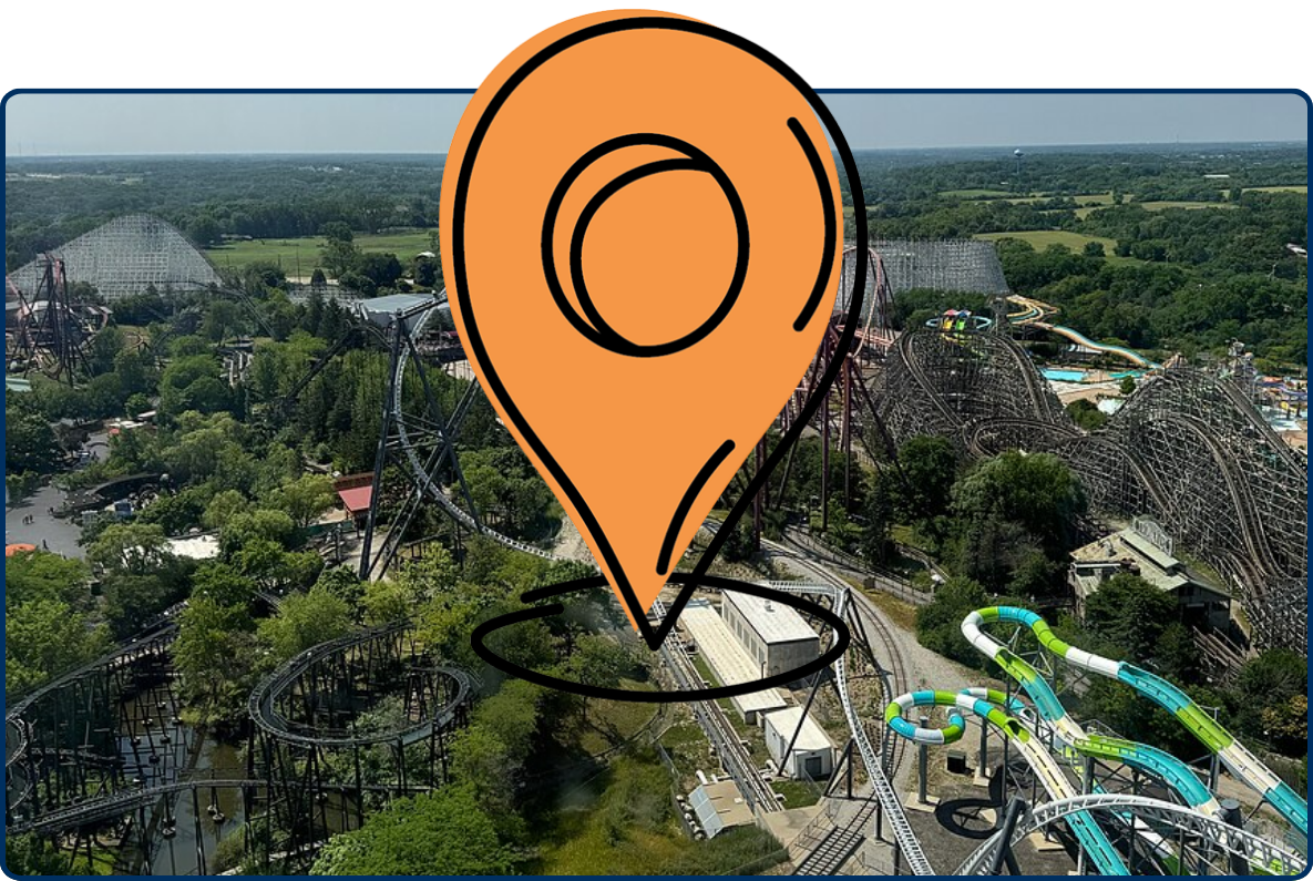 Aerial view of Six Flags Great America with roller coasters, water slides, trees, and distant landscape.