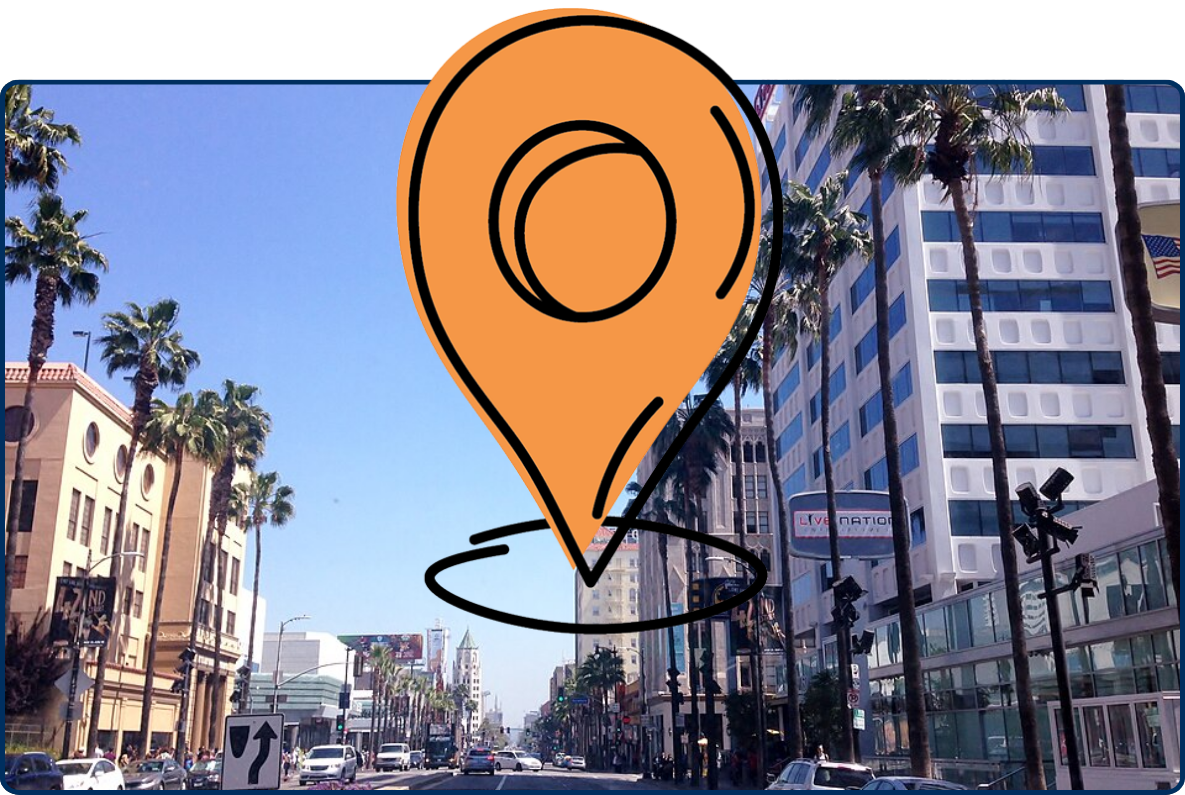 Hollywood Boulevard in Los Angeles with palm trees, city buildings, traffic, and a clear blue sky.