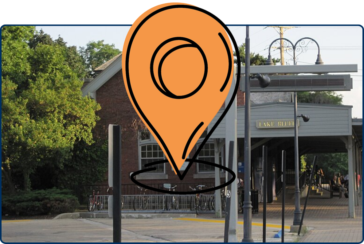 Lake Bluff Metra Station with brick station building, train platform, tracks, lamps, and surrounding trees.
