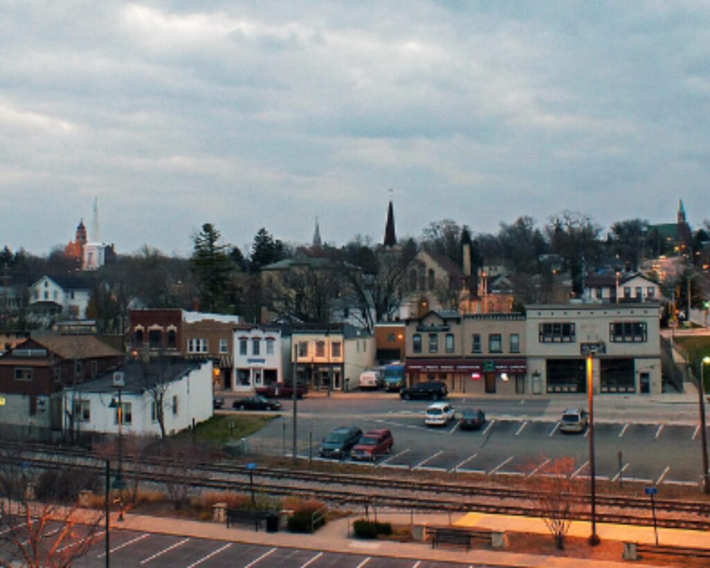 Lemont town view with railroad tracks, buildings, trees, and cloudy evening sky.