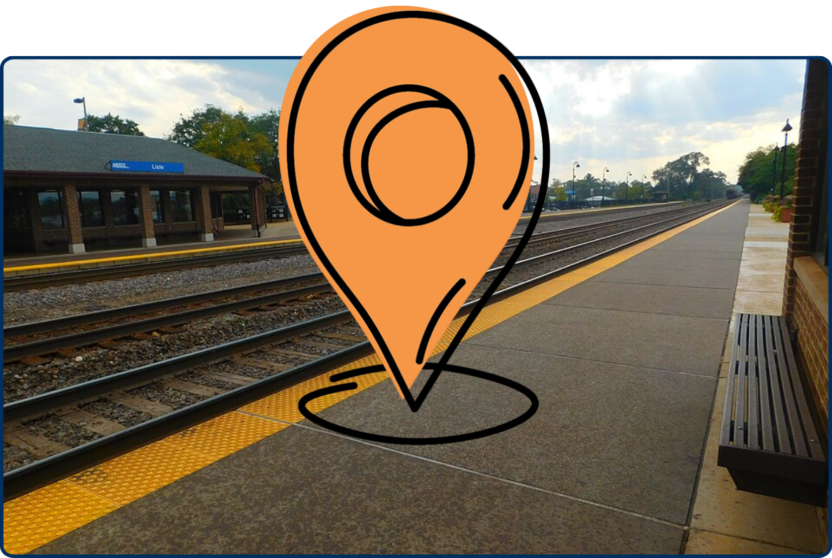 Lisle Station platform with railroad tracks, station building, bench, and cloudy sky.