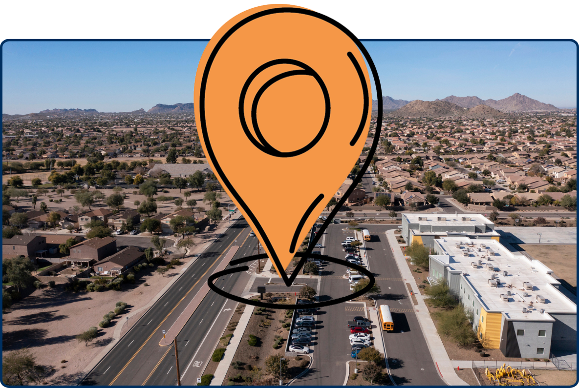 Aerial view of San Tan Valley, Arizona with suburban homes, a long road, school building, desert landscape, and distant mountains.