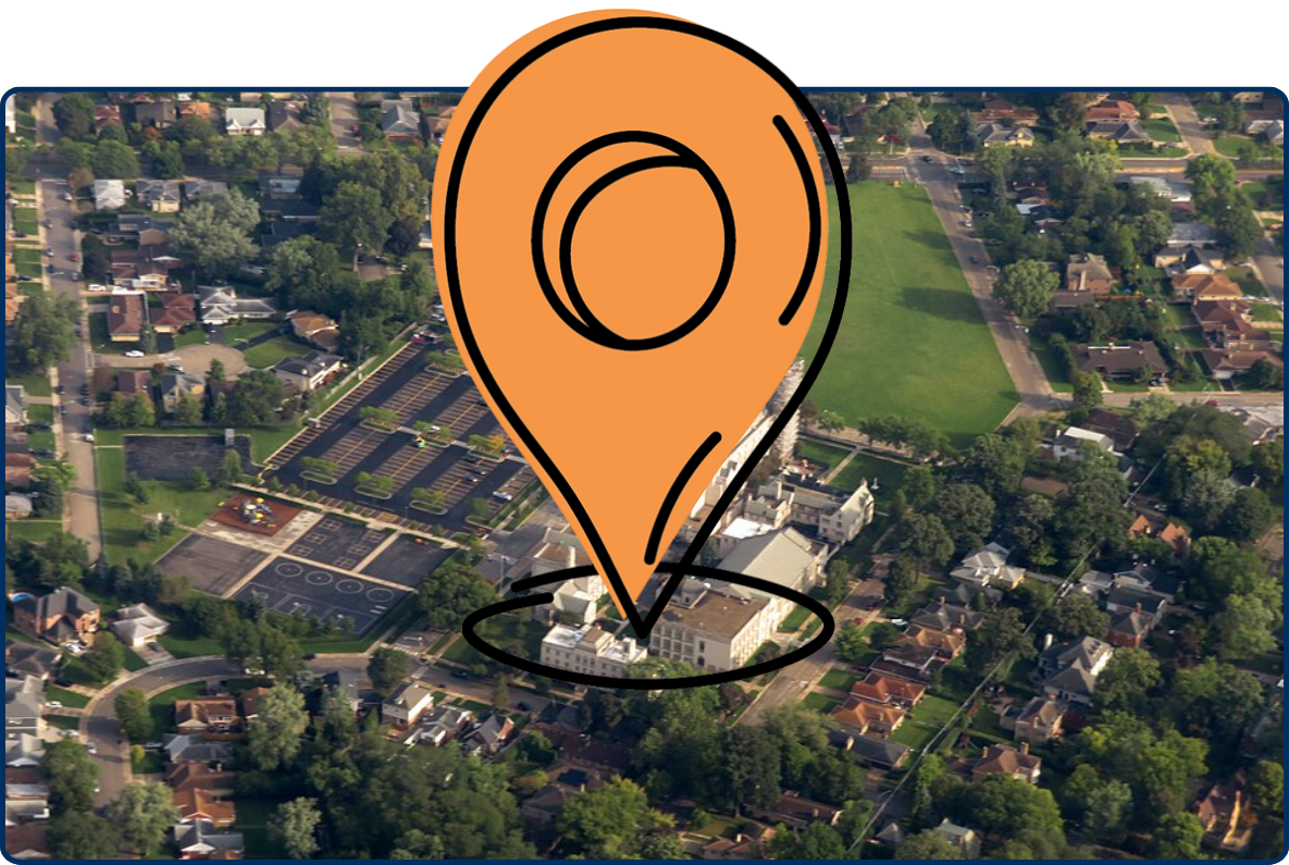 Aerial view of Queen of All Saints Basilica surrounded by homes, trees, parking lots, and green fields.