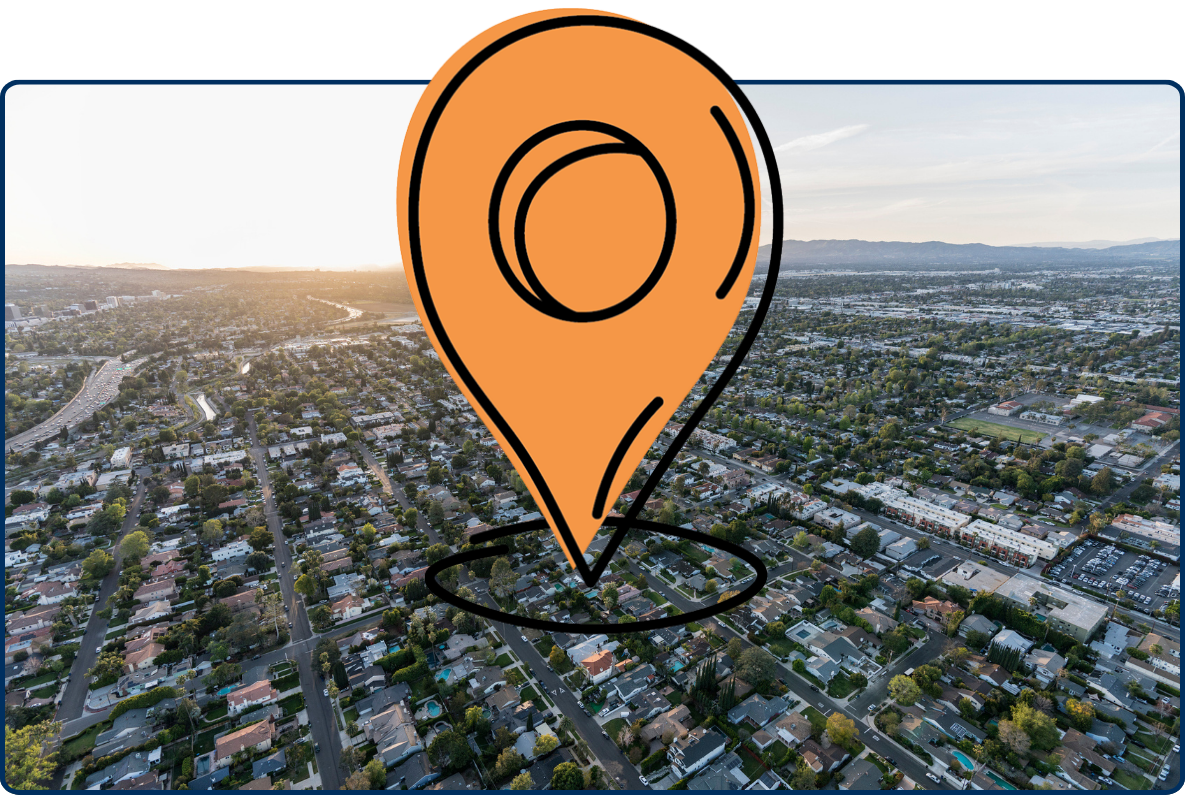 Aerial view of Van Nuys, Los Angeles at sunset with suburban homes, roads, and distant mountains.