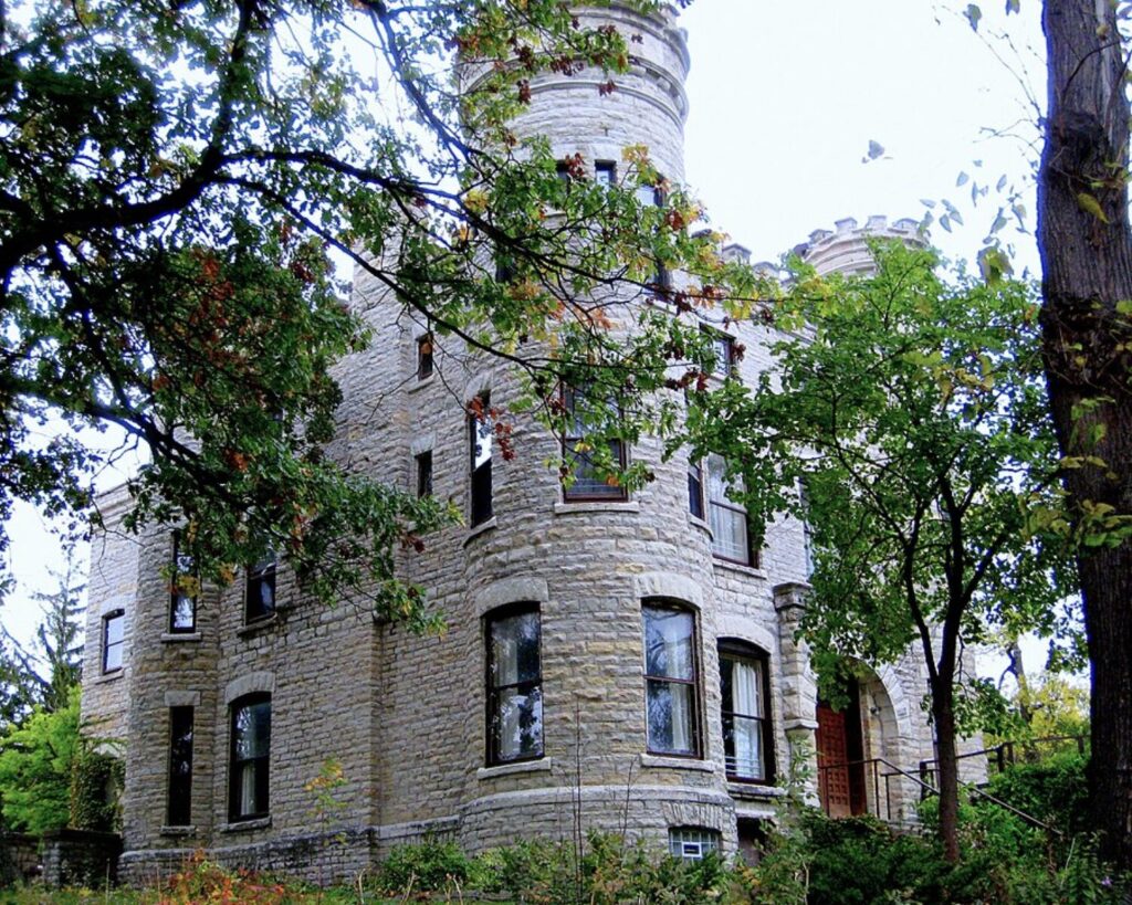 Historic Givens Irish Castle in Chicago, featuring stone walls, turreted towers, and surrounding trees.
