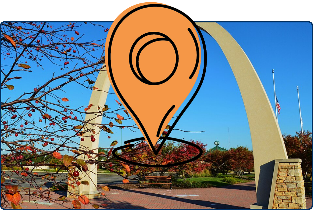 Carol Stream park arch with autumn branches, red berries, flags, and clear blue sky.