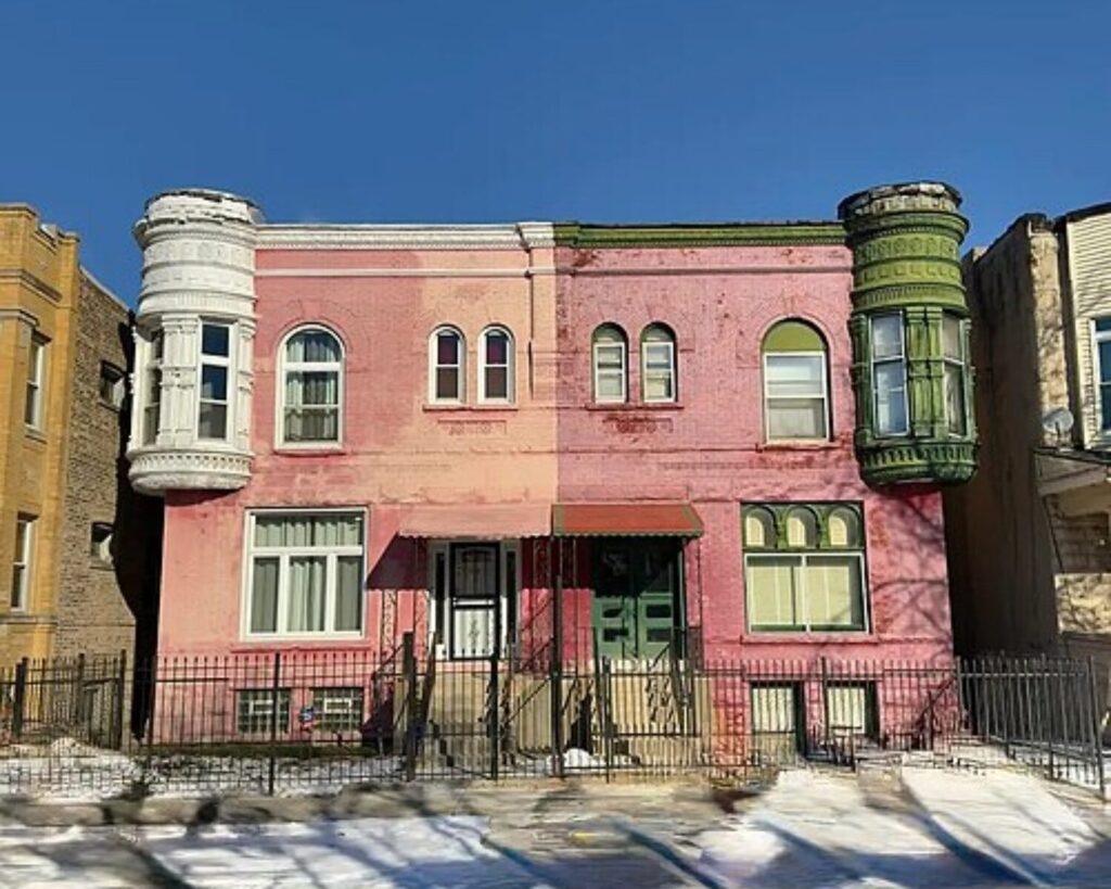 Pink two-story building with white and green bay windows along a snow-covered Chicago street under a clear blue sky.