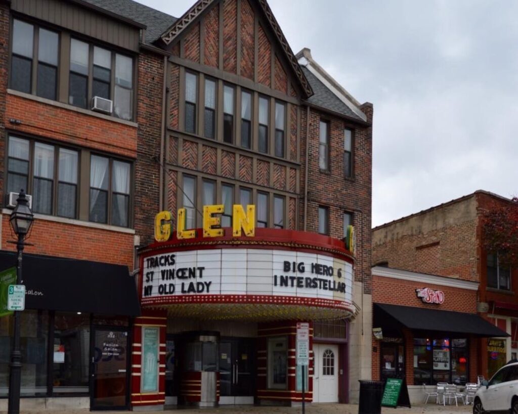 The Glen theater marquee on a brick building, with yellow GLEN letters and movie titles on the marquee