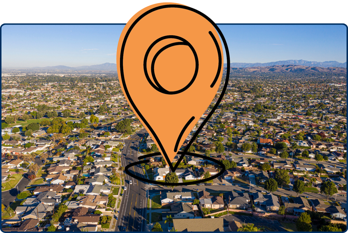 Aerial view of Los Angeles County homes with suburban streets, greenery, and mountains in the background.