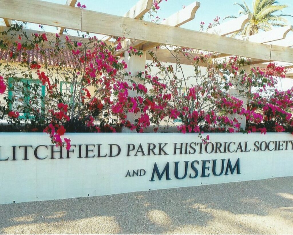 Litchfield Park Historical Society and Museum sign with pink flowers, pergola, and desert-style building.