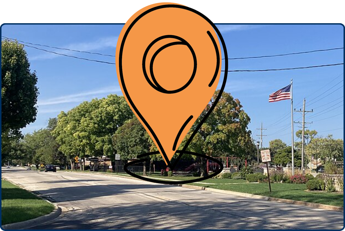 Commissioners Point Park in Niles with a tree-lined roadway, landscaped entrance sign, and American flag under a clear blue sky.