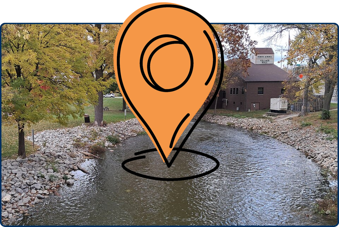 Rock-lined river flowing through North Aurora Riverfront Park beside Village Hall, surrounded by autumn trees.