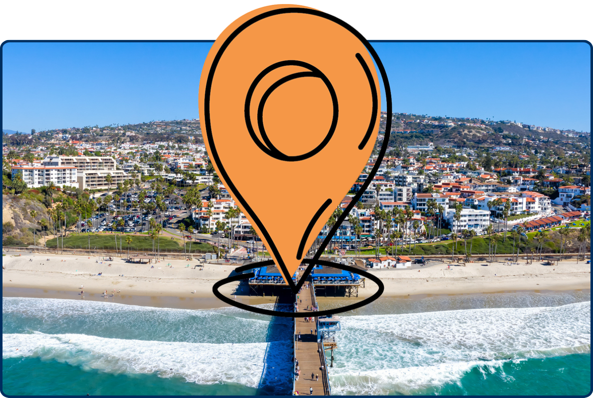Aerial view of San Clemente, California, with beach, ocean waves, pier, coastal buildings, and hillside homes.