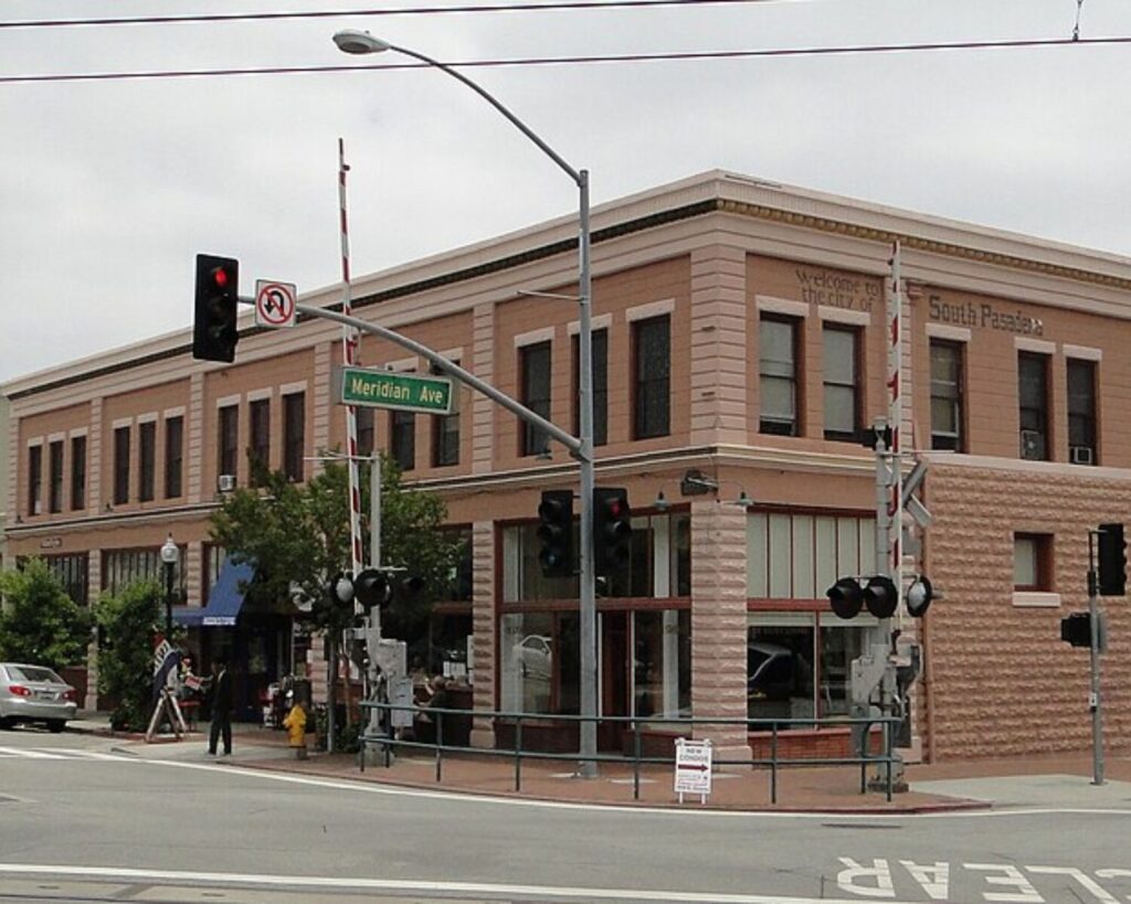 South Pasadena Historic District street corner with brick buildings, traffic lights, parked cars, and railroad crossing signals.