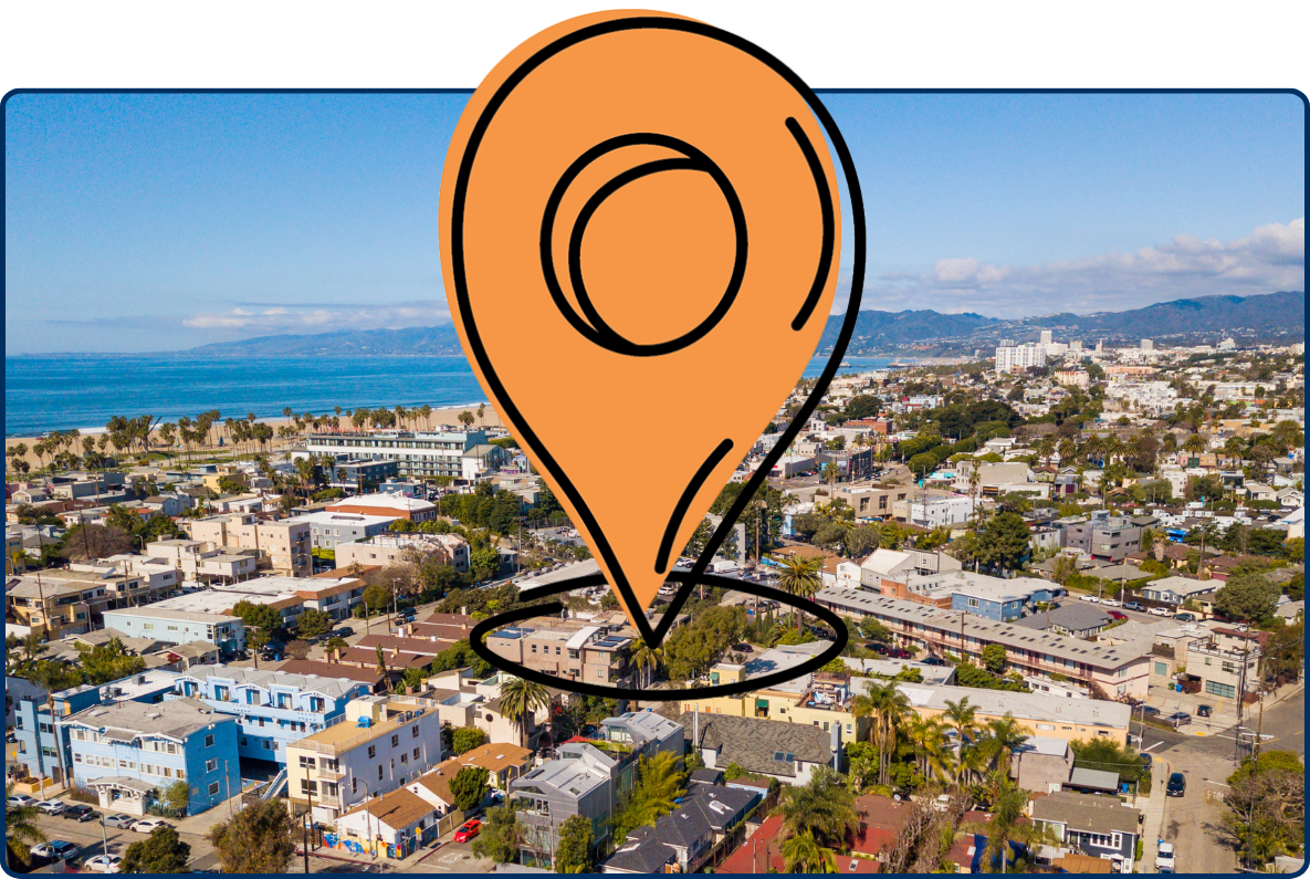 Aerial view of Venice, Los Angeles, featuring coastal neighborhoods, the Pacific Ocean, and distant mountains.
