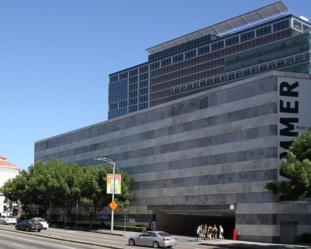 Hammer Museum exterior in Los Angeles with modern building facade, street traffic, trees, and clear blue sky.