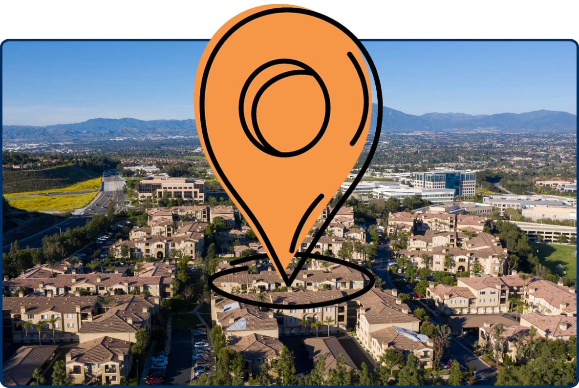 Aerial view of Aliso Viejo, California, with residential neighborhoods, office buildings, green hills, and mountains in the distance.