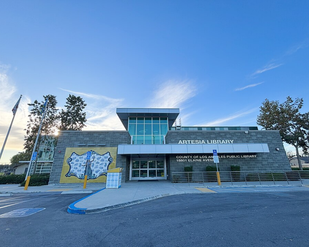 Exterior of the Artesia Library, a modern County of Los Angeles Public Library building with a mural, glass entrance, and accessible parking.