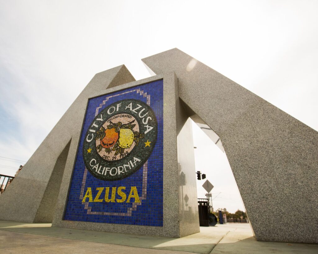 Mosaic City of Azusa sign embedded in a concrete arch at an entrance.