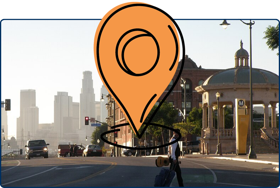 Street scene near 1st Street in Los Angeles with a pedestrian crossing, Metro entrance, historic buildings, and the downtown skyline in the background.