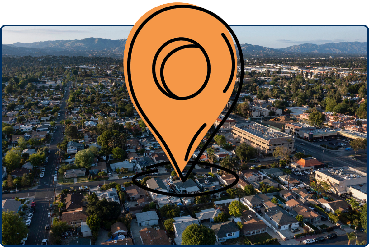 Aerial view of Canoga Park, Los Angeles, with residential neighborhoods, commercial buildings, tree-lined streets, and mountains in the distance.