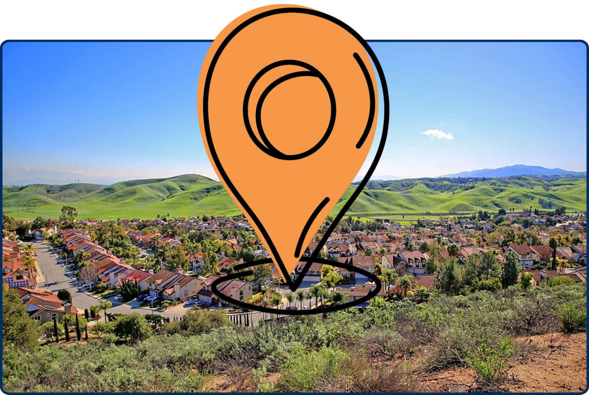 Panoramic view of Diamond Bar, California, with residential neighborhoods surrounded by rolling green hills under a clear blue sky.