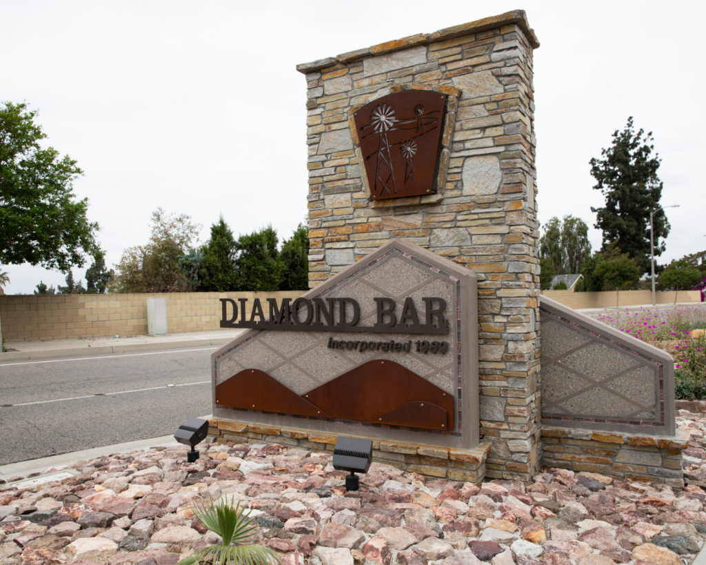 Diamond Bar entrance sign mounted on a stone pillar with landscaped rocks and desert plants nearby.