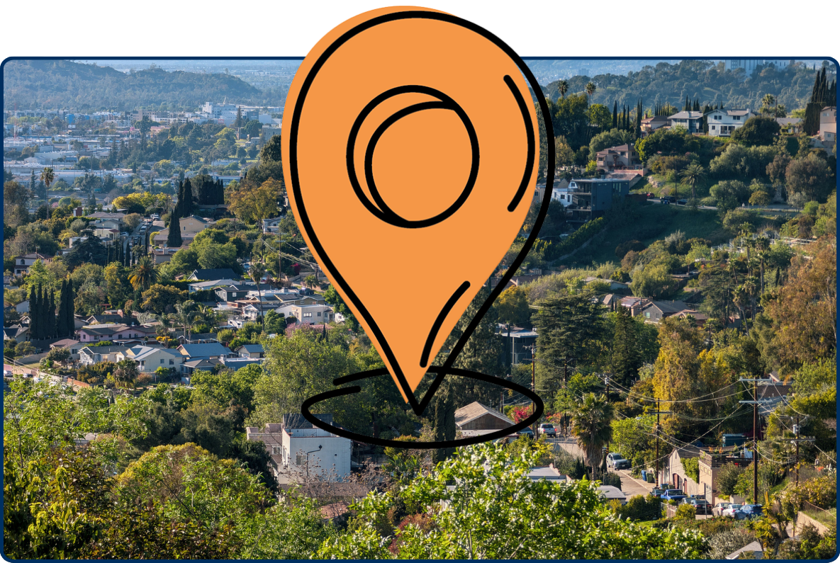 Panoramic view of Glassell Park in Los Angeles, with hillside homes, dense greenery, and mountain ranges in the distance.