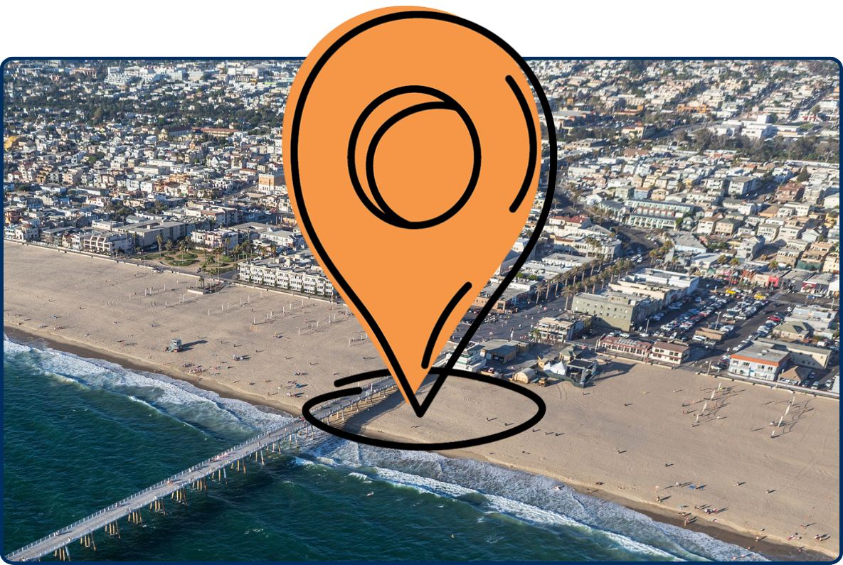 Aerial view of Hermosa Beach, California, with a long pier extending into the Pacific Ocean and a dense coastal neighborhood along the sandy shoreline.