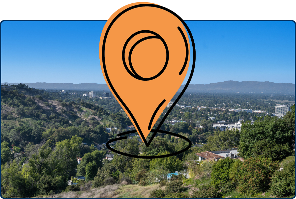 Panoramic view of Hidden Hills, California, with lush green hills, tree-covered neighborhoods, and distant mountains under a clear blue sky.