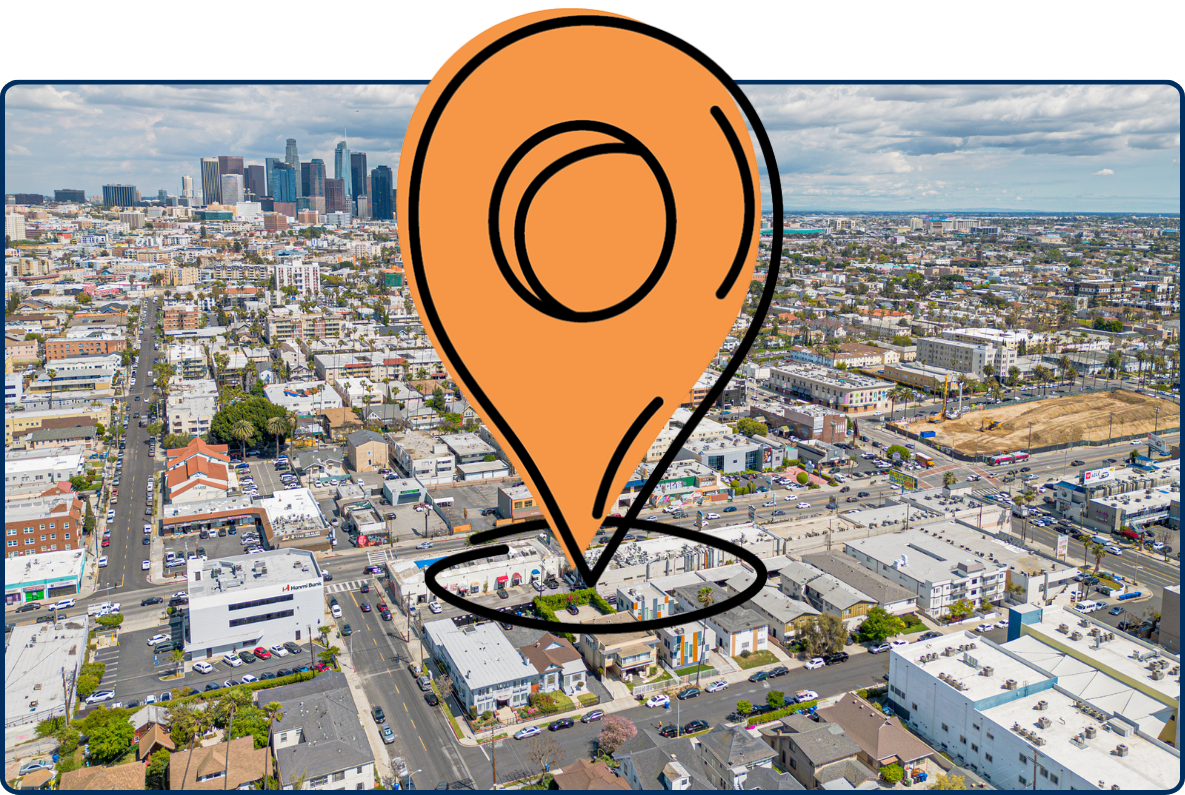 Aerial view of Los Angeles’ Koreatown near Olympic Boulevard and Vermont Avenue, with dense city blocks and the downtown skyline in the distance.