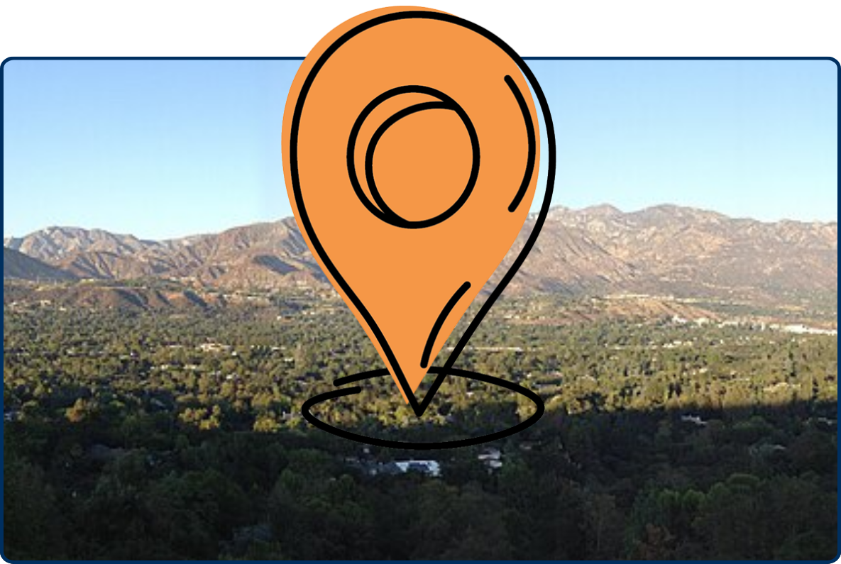 Panoramic view of La Cañada Flintridge, California, with tree-covered neighborhoods spread across the valley beneath rugged mountain ranges.