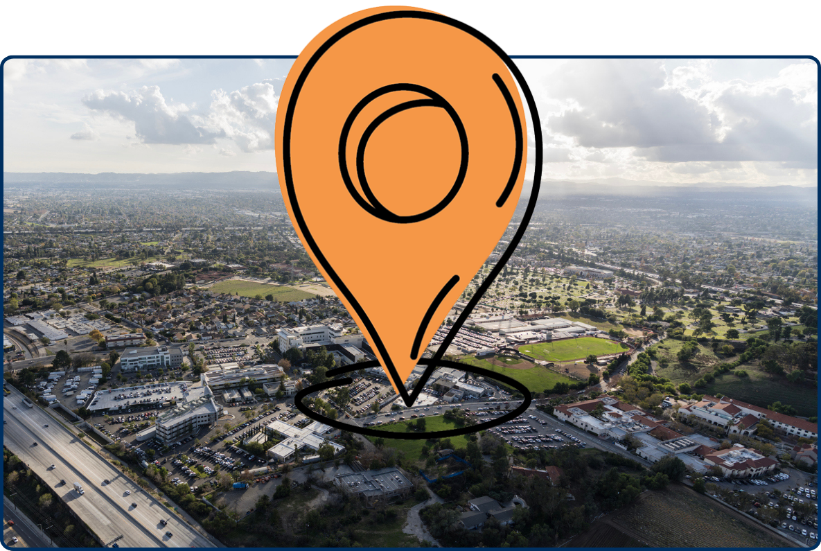 Aerial view of Mission Hills, California, showing a freeway, residential neighborhoods, green spaces, and distant hills under a cloudy sky.