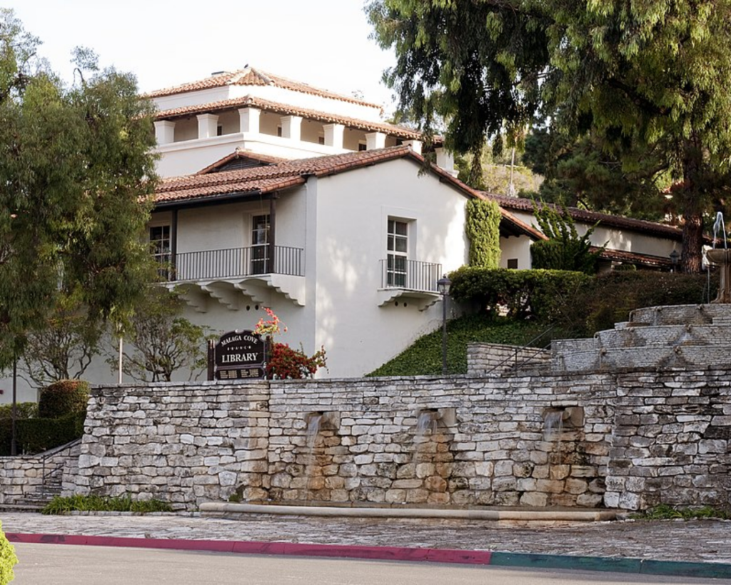 Malaga Cove Library in Palos Verdes Estates, featuring Spanish-style architecture, tiled roofs, stone walls, and surrounding trees.