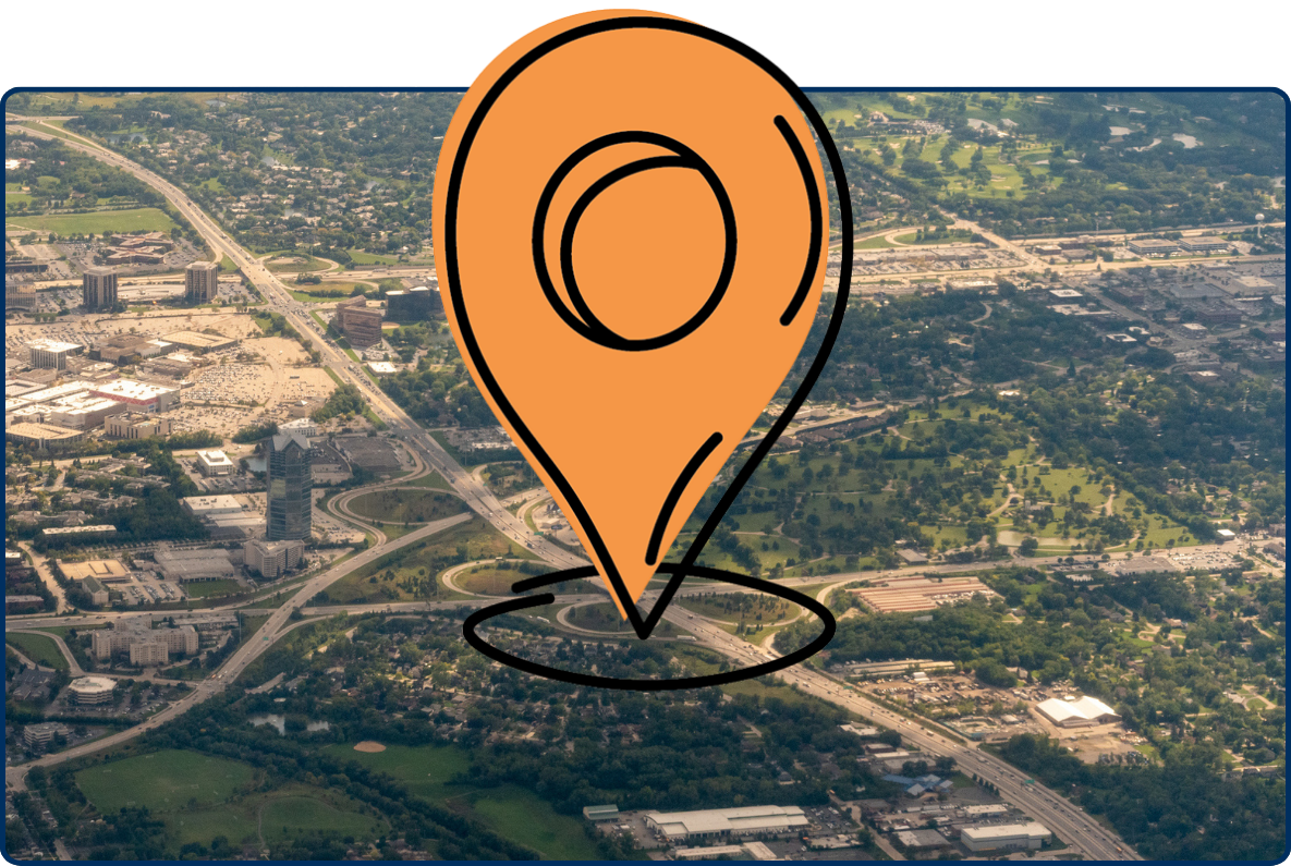 Aerial view of an interstate highway interchange surrounded by office buildings, residential neighborhoods, and green spaces.