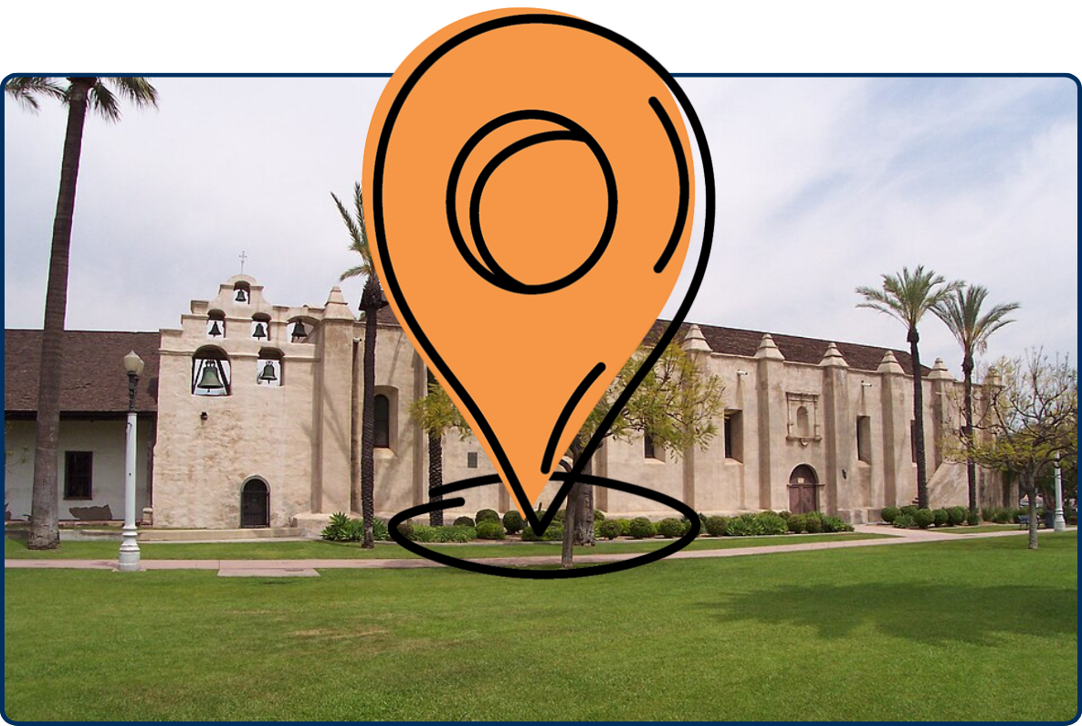 Mission San Gabriel Arcángel in California, featuring historic adobe-style architecture, a bell wall, palm trees, and a green lawn.