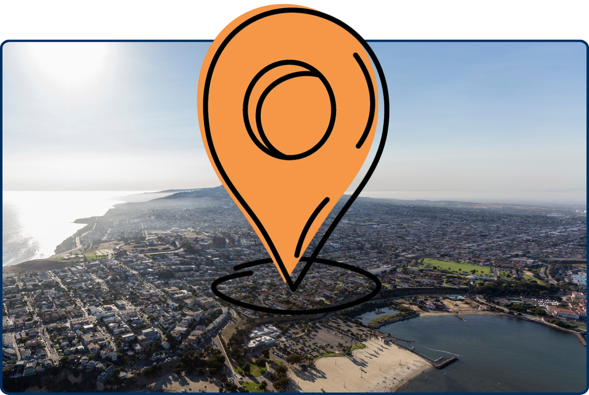Aerial view of the San Pedro coastline in Los Angeles, showing ocean cliffs, dense neighborhoods, beaches, and distant hills under bright sunlight.