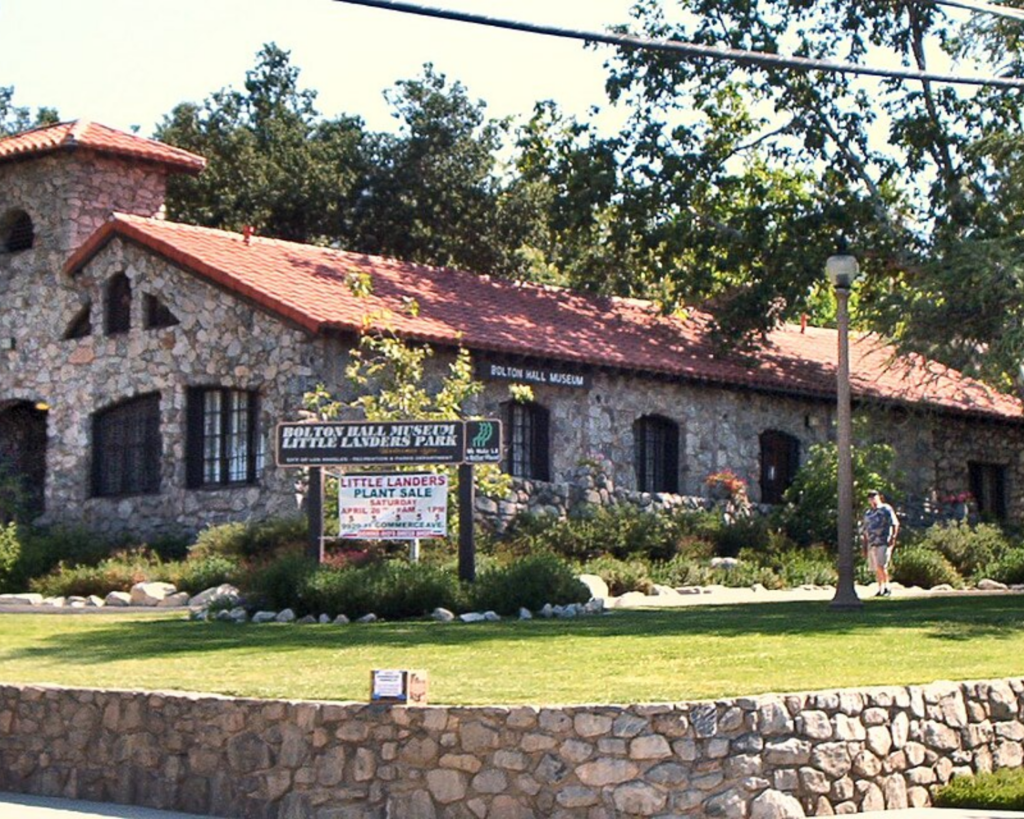 Bolton Hall Museum in Tujunga, California, featuring a historic stone building with a red-tiled roof, landscaped lawn, and surrounding trees.
