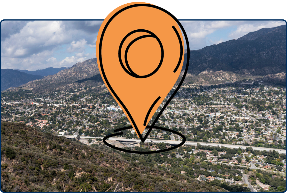 Aerial view of Tujunga and Crescenta Highlands, California, with hillside neighborhoods, a freeway, rugged mountains, and dramatic clouds.