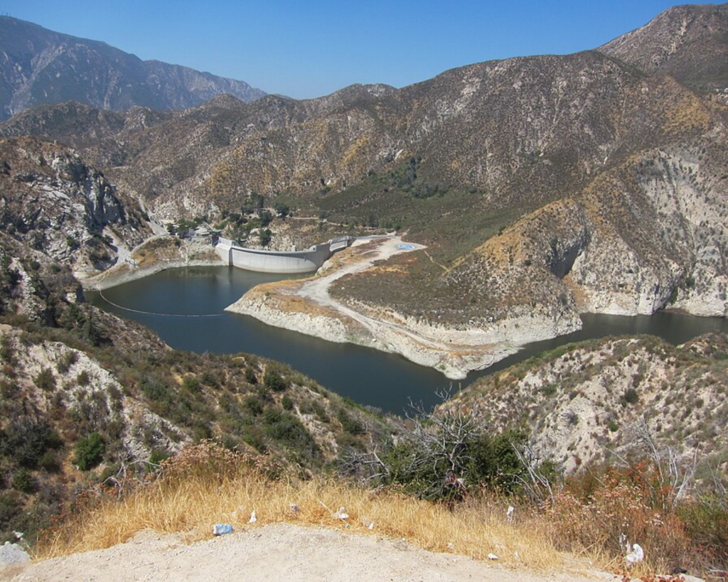 Big Tujunga Reservoir in California, surrounded by rugged mountains and dry hills, with a dam visible across the water.