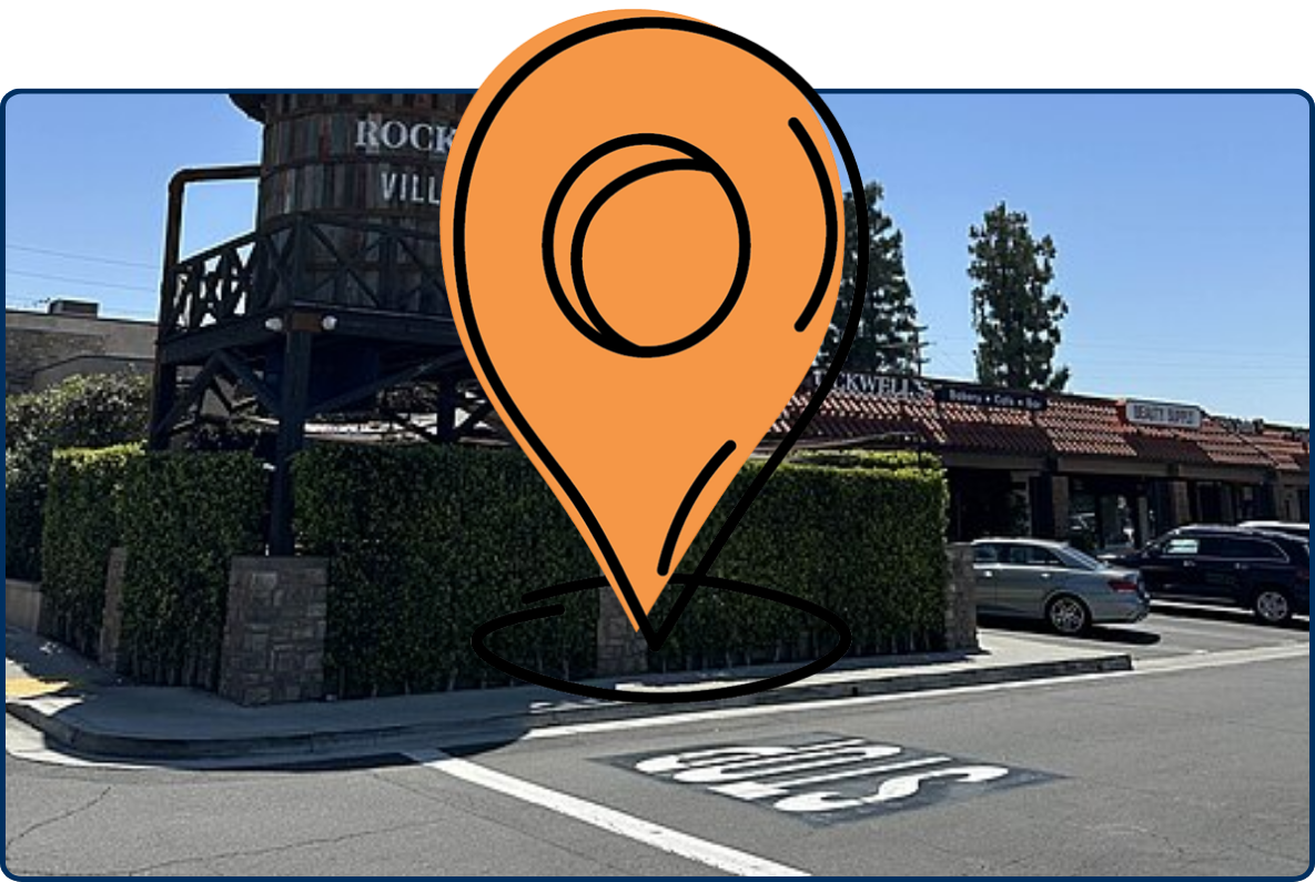 Villa Park town center in California, featuring a rustic water-tower-style landmark, shops, parked cars, and a clear blue sky.