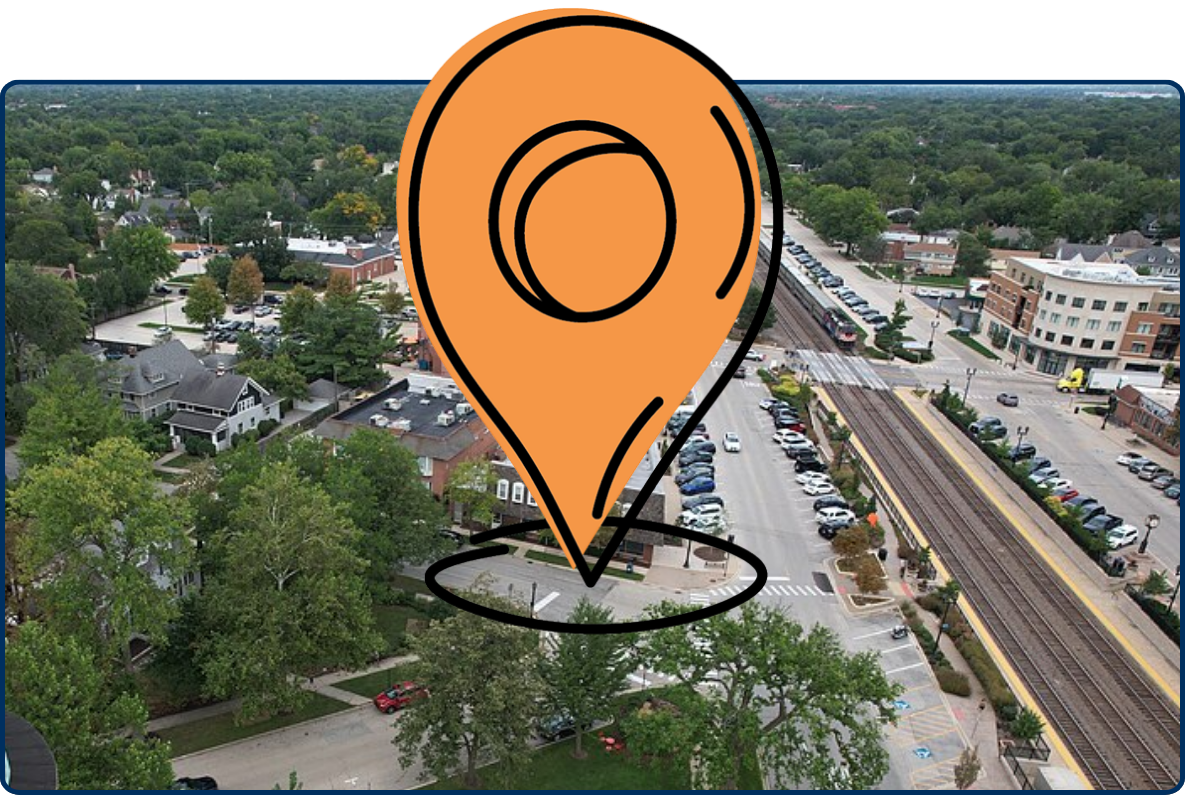 Aerial view of Western Springs, Illinois, with the historic water tower, tree-lined neighborhoods, downtown buildings, and railroad tracks.