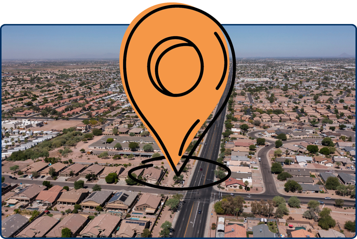 Aerial view of Apache Junction, Arizona, showing expansive residential neighborhoods, a long straight roadway, desert landscaping, and low-density development stretching toward the horizon.